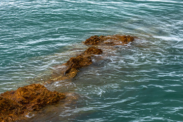 Obraz premium Sea waves breaking on a rocks. Deep blue sea waves hit cliff, hit rocks cliff. Mighty sea waves breaking on a cliff, splashing over rocks. Strong ocean waves hitting rocks.