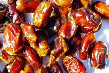 sweet dried dates lie on a white plate, bright sunlight