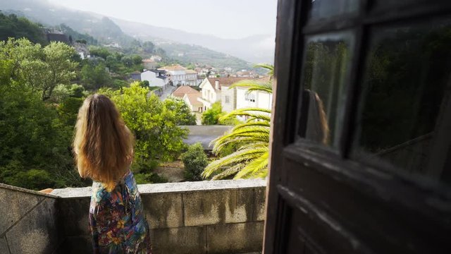 From above woman with crossed hands on balcony of traditional country house in valley of Douro river in winemaking region in Portugal