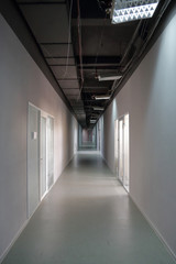 Fototapeta premium Długi wąski korytarz z drzwiami w biurze lub miejscu pracy