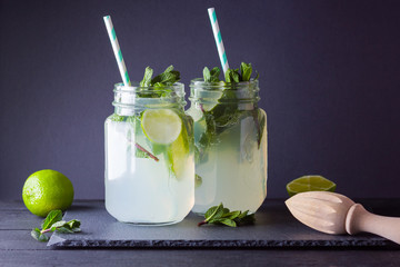 Mojito and mint on black background. Refreshing cocktail with lime and fresh mint on slate board....