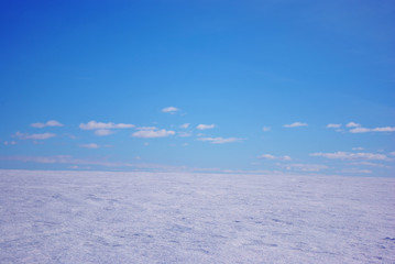 Fototapeta na wymiar Field covered with snow, winter landscape, bright blue cloudy sky