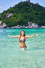 The girl is smiling and looking at the camera, splashing water, swimming in a beautiful bay