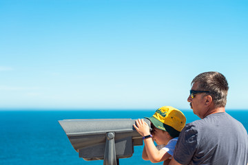 Grandfather and grandson observing Kangaroo Island coast through outdoor binocular
