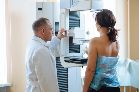 Male doctor Standing Assisting Female Patient Undergoing Mammogram X-ray Tes