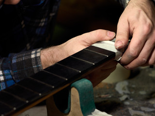 In the guitar workshop, Guitars Luthiers installs Nut.