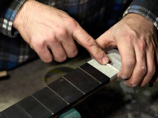 In the guitar workshop, Guitars Luthiers installs Nut.