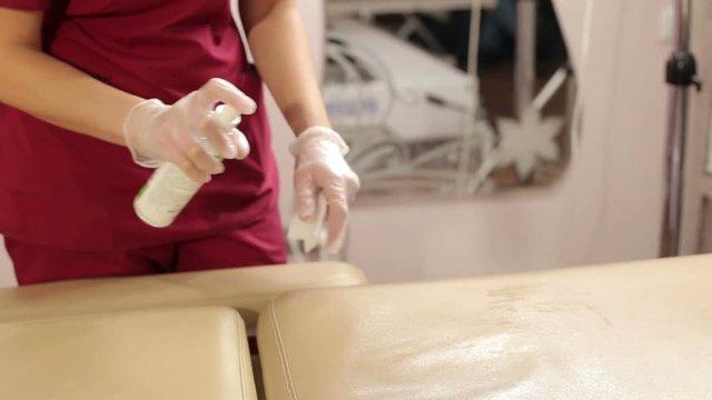The beautician wipes disinfectant wipe chair in the beauty parlor. Preparation of a cosmetology chair for the procedure shugaring. Disinfection cosmetology chairs and tools.