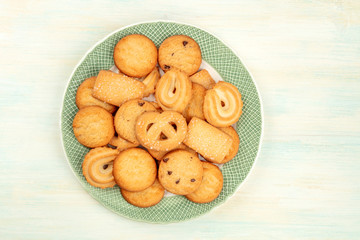 Danish butter cookies on a plate, shot from the top on a white wooden background with copy space