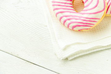 Donut on a kitchen towel and on a wooden table. Photo of sweets with copyspace.
