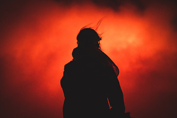 Dark person standing in front of active volcano (erta ale in ethiopia)