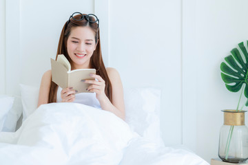 Obraz na płótnie Canvas beautiful attractive asian woman enjoy reading book on bed portrait of asian long hair woman enjoy weekend activity white bedroom