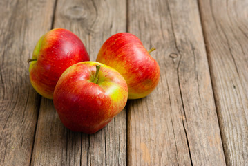 Fototapeta na wymiar three apples on old wooden background