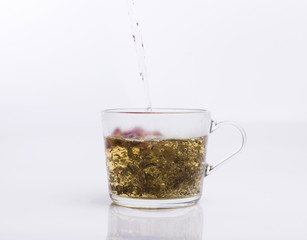 Tea pouring into glass cup isolated on white background