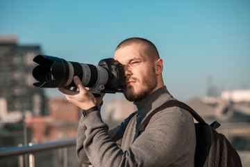 Handsome young photographer with beard is taking pictures. Business process