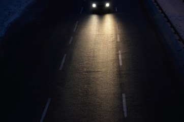 Auto with high beam driving on the winter road at night.