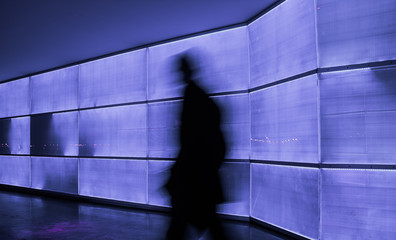 silhouette of unrecognizable person in a neon passageway with blue and violet lights