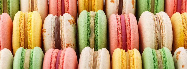 Rows of colorful french macarons - green, yellow and pink.