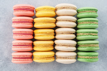 Rows of various colorful french macarons, gray background.
