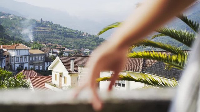Crop woman on balcony of traditional country house in valley of Douro river, winemaking region of Portugal. Beautiful view landsape with mountain and clouds in sunny day