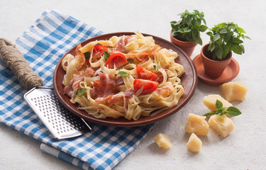 Classic pasta Carbonara, with bacon, egg, Parmesan cheese and Basil on a light background. Pieces of Parmesan, Basil and cheese grater are next to the table.