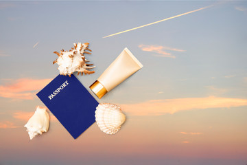 Passport, sun creen cream and shells, sky