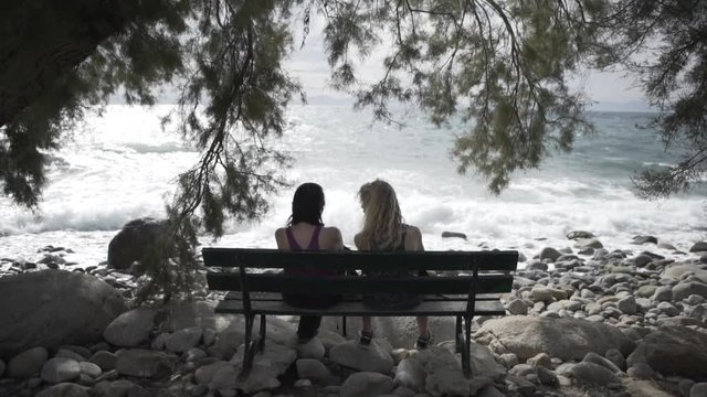 Women resting on bench with coast ocean view in slow motion