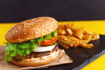burger and french fries on a yellow table with a dark background and space for text