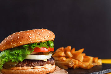 burger and french fries on a yellow table with a dark background and space for text