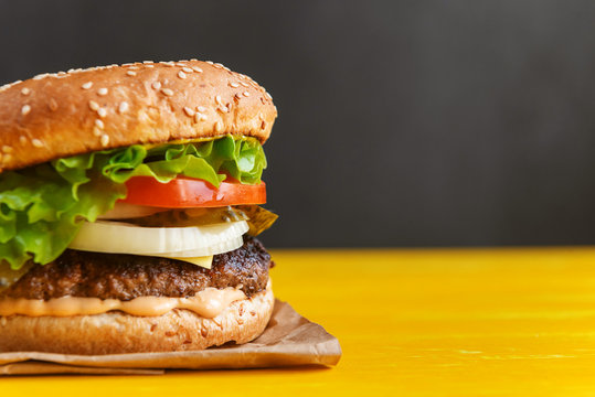 Burger On A Yellow Table And A Dark Background With Space For Text