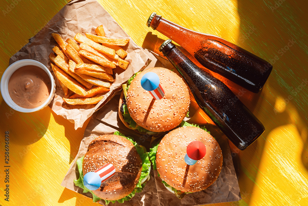 Wall mural three fresh and juicy burgers with American flag-style fireworks inserted into them. bbq concept picnic to celebrate independence day