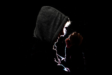 silhouette of male fighter in the hood in the darkness - Powered by Adobe