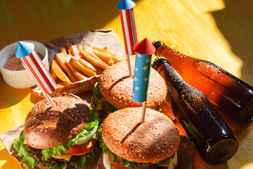 three fresh and juicy burgers with American flag-style fireworks inserted into them. bbq concept...