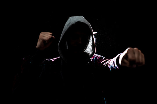 silhouette of male fighter in the hood in the darkness