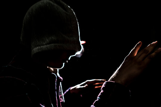 silhouette of male fighter in the hood in the darkness