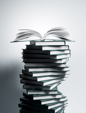 A spiral of stacks of books in the form of DNA and an open textbook at the top.