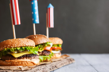three fresh and juicy burgers with American flag-style fireworks inserted into them. bbq concept...