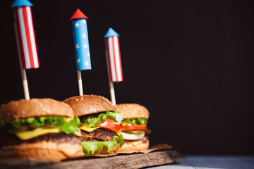 three fresh and juicy burgers with American flag-style fireworks inserted into them. bbq concept...