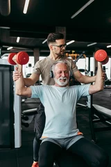Gordijnen Senior man exercising in gym with his personal trainer. © hedgehog94