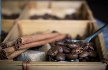 Lots of coffee beans, sugar cubes and cinnamon sticks by wooden box.
