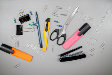 Fototapeta na wymiar Flat lay, layout on a gray background: stationery, scissors, stapler, pens, markers, paper clips, clips, calculator
