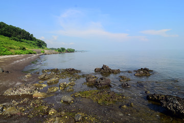 Jodo beach scenery background in the stem area (Central Java). with two views, land and sea. there are beach rocks, beach sand, bright blue sky, and some plants along the coast