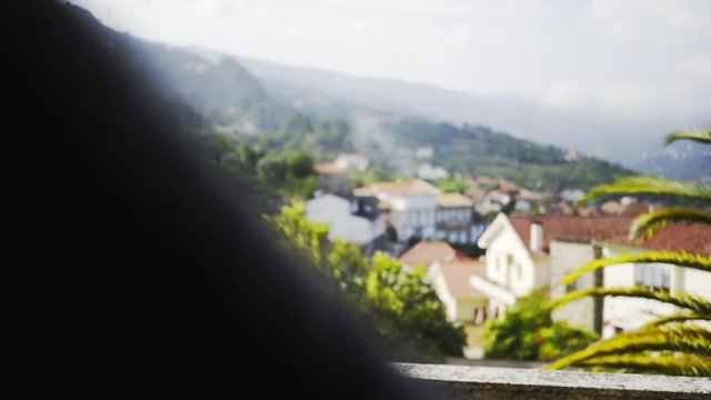 Crop woman hand opening door in dark room on balcon of traditional country house and beautiful view above typical village in valley of Douro river, winemaking region of Portugal.