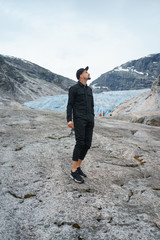 portrait of young traveler rock climber on the background of spellbinding landscape of Norwegian nature with high charming mountains and hills