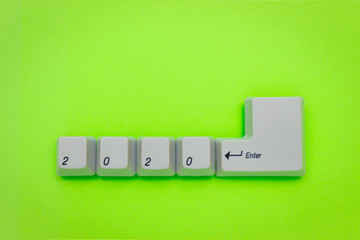 Computer keyboard keys with 2020 enter written using the white buttons on green background. New year technology concept. New year 2020 card with copyspace.
