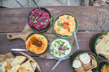 four dips served on a rustic platter photographed from above