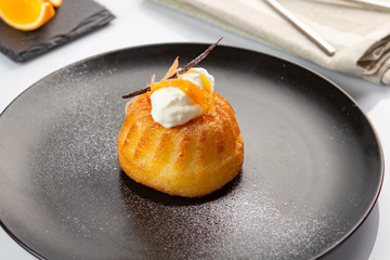 Italian sweet dessert  Baba of Naples with orange liqueur, biscuit cake in a black plate