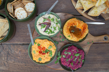 four dips served on a rustic platter photographed from above