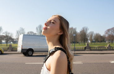 Teenage girl walking on the pavement with a road behind her