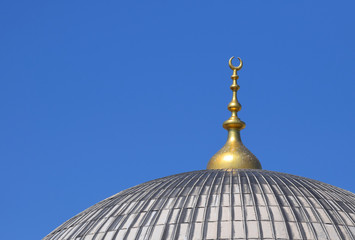 Fototapeta na wymiar The dome of a mosque with a golden crescent moon against blue sky